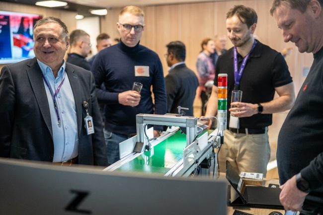 Uczestnicy konferencji AI Lab Day obserwujący działanie zautomatyzowanej linii do sortowania paczek w strefie Experience Zone, co ilustruje praktyczne wdrożenia technologii AI w procesach logistycznych przemysłu.
