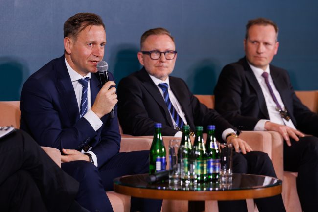 Eksperci na scenie podczas debaty o tym, jak inwestycje strategiczne i megaprojekty wpłyną na Polskę w dobie globalnych konfliktów. Jeden z prelegentów zabiera głos w warszawskim hotelu Regent.